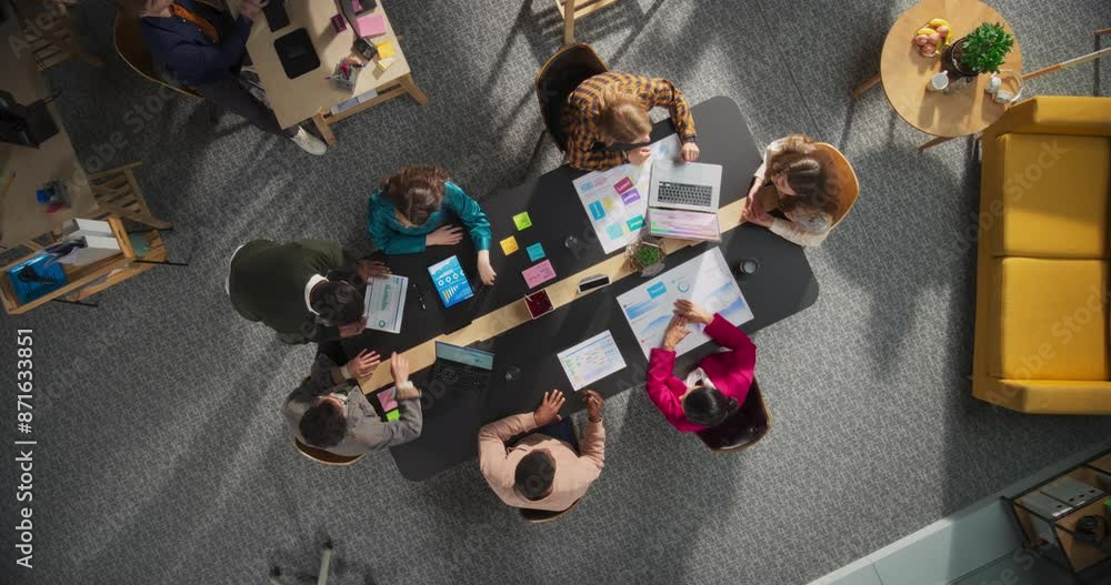 Poster top down view: diverse team of professionals collaborating on digital projects in a corporate office