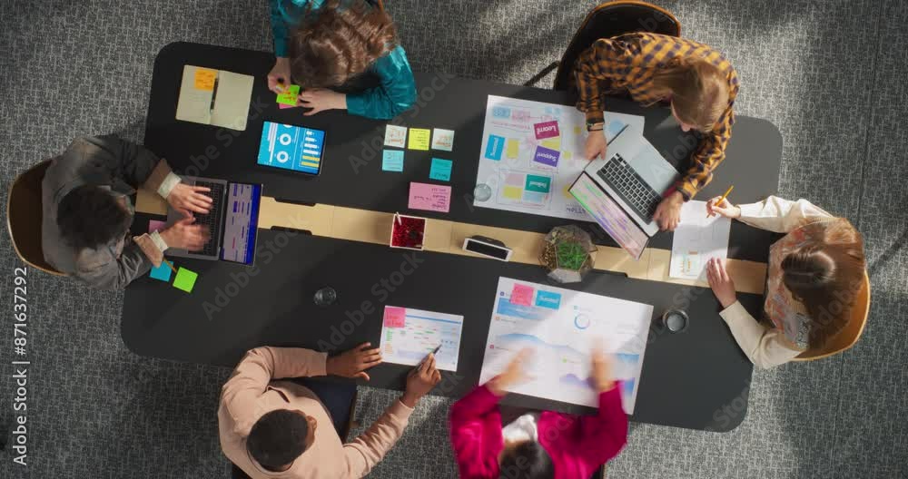 Poster Top Down View: Diverse Team of Professionals Brainstorming and Analyzing Data in an Office. Businesspeople Collaborate on Digital Projects Using Laptops, Charts, and Infographics. Time Lapse Shot.