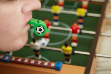 Referee blows a sports whistle with a foosball background, game start, game end in a foosball game,...