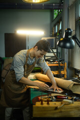 Tailor leather craftsman measuring leather for sewing at his workshop