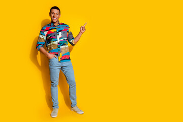 Fototapeta premium Full length photo of nice young male point empty space dressed stylish colorful garment isolated on yellow color background