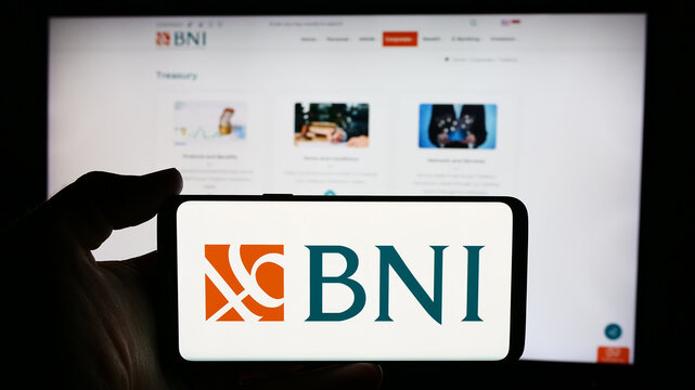 Stuttgart, Germany - 06-24-2024: Person holding cellphone with logo of Indonesian financial company Bank Negara Indonesia (BNI) in front of webpage. Focus on phone display.