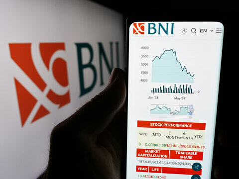 Stuttgart, Germany - 06-24-2024: Person holding cellphone with webpage of Indonesian financial company Bank Negara Indonesia (BNI) with logo. Focus on center of phone display.