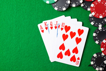 Casino chips and poker cards on a green mat