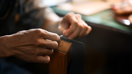 Close up craftsman meticulously stitching leather with a needle and thread. Leather craft concept