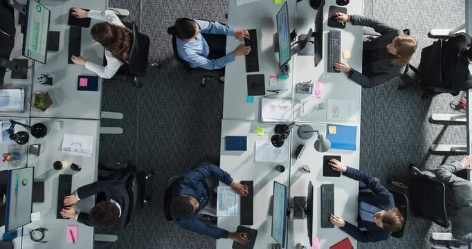 Top Down View of Diverse Team Working on Desktop Computers in an Office. Collaborative Environment With Constant Activity, Discussions, and Document Sharing, Creating an Efficient Workspace.