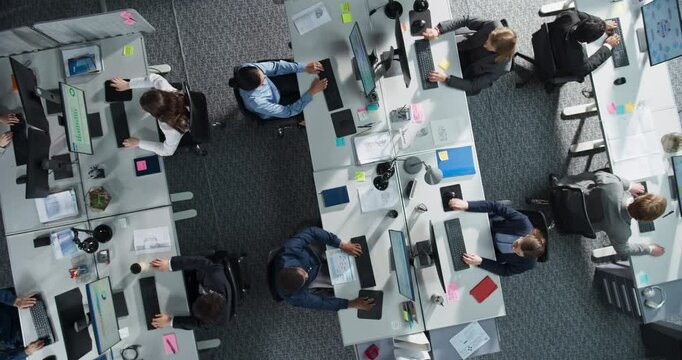Top Down View of Diverse Team Working on Desktop Computers in a Corporate Office. Collaborative Environment With Constant Activity, Discussions, and Document Sharing, Creating an Efficient Workspace.