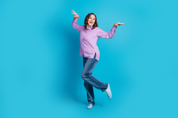 Full length photo of charming positive woman wear violet shirt dancing empty space isolated blue color background