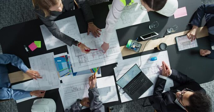 Top Down View Zoom Out: Diverse Engineers, Business Developers, Construction Coordinators Gathered Around The Table to Discuss Real Estate Project Architectural Plan, Using Laptop, Tablet In Office.