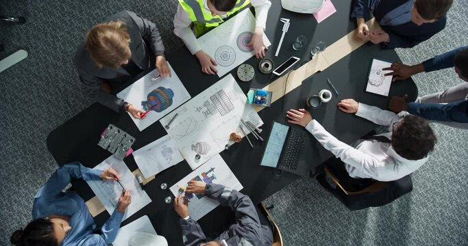 Zoom Out Top Down View: Diverse Team of Business Professionals and Construction Engineers Working With Blueprints Of Industrial Machinery in An Office. Teamwork Of Colleagues With Laptop, Tablet
