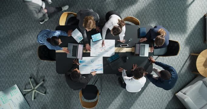 Zoom Out Top Down View: Diverse Team Of Business Professionals With Laptops Entering The Conference Room And Sitting Behind Table To Discuss Financial Data And Project Mindmap in Modern Office.