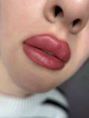permanent makeup on the lips of a young woman of a delicate peach shade close-up, a girl after a...
