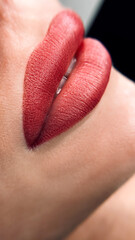 permanent makeup on the lips of a young woman of a delicate peach shade close-up, a girl after a...
