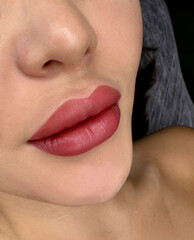 permanent makeup on the lips of a young woman of a delicate peach shade close-up, a girl after a...