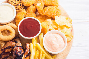 Onion rings , nuggets grilled wings , french fries mix of snacks and sauces . Beer board