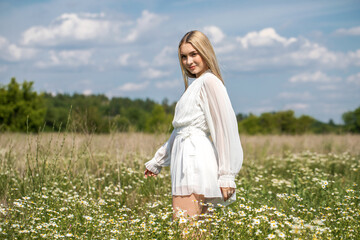 Portrait of a young beautiful blonde in a chamomile field