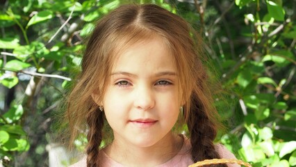 Cute girl tasting picked strawberries in the garden. Smiling girl holding strawberries in the garden. Happy child enjoying fresh picked strawberries in the garden