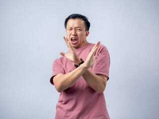 A man in a pink shirt crosses his arms in front of him with a disapproving expression, as if saying...