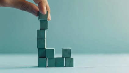 A hand leans on green and blue wooden blocks shaped like a graph, rising up to create a bar chart or growth