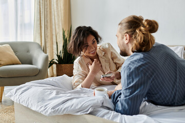 A couple relaxes on their bed, enjoying a cup of coffee and a conversation.