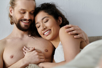 A man and woman share a loving embrace in bed, enjoying a peaceful morning together.