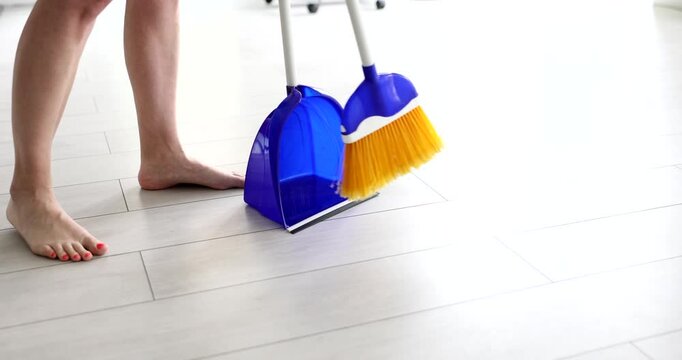 Woman sweeping floor with broom and dustpan closeup 4k movie slow motion. Apartment cleaning and household chores concept