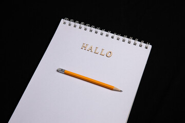 Leeres Papier mit Bleistift und Schriftzug HALLO aus Holz