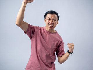 A man in a pink shirt raises both fists in a celebratory gesture, his face beaming with excitement...