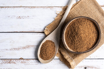 Coconut palm sugar in a wooden bowl on white wooden table background. Top view. Copy space