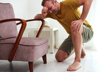 Man with painful knee and leg injury at home.