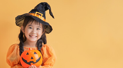 A cute and happy Southeast Asian girl dressing in a Halloween costume and holding an orange Jack o' lantern on a plain orange background with copy space for text.