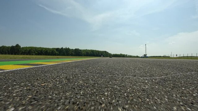 POV: Chasing the race leader on during an adrenaline filled automotive race in the sunny countryside. Speeding around the corners of a race circuit, chasing the car ahead. Amateur motorsport racing