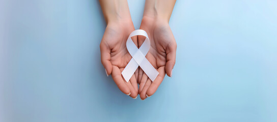  Hands  holding white cancer awareness ribbon. Symbol for cancer, domestic violence. World Lung Cancer Day. International Epilepsy Day. World Alzheimer's day. World. Health and treatment concept