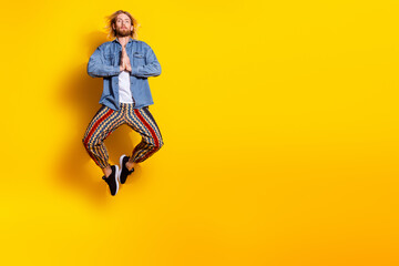 Full length photo of handsome young male jump meditate pray dressed stylish denim garment isolated on yellow color background