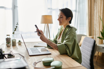 A woman working at home, looking at her phone.
