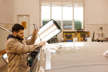 Mechanic performing dent repair in his garage