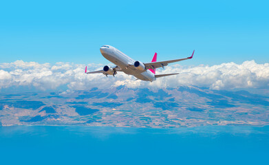 White passenger airplane flying in the sky amazing clouds in the background - Travel by air...