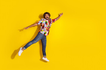 Full size photo of pretty young guy jump flying wear trendy colorful outfit isolated on yellow color background