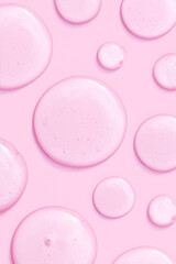 round drops of transparent gel serum on pink background