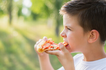 Cute child eating pizza in nature in summer