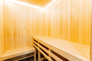 A wooden sauna with benches and a light on the ceiling