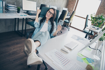 Photo of lucky good mood lady agent dressed jeans shirt winning game modern gadget indoors...