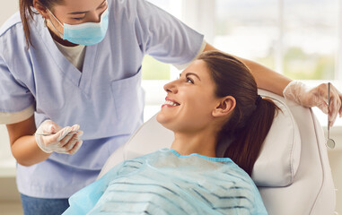 Doctor dentist, nurse, or orthodontist conducting a dental examination for a smiling patient in the...