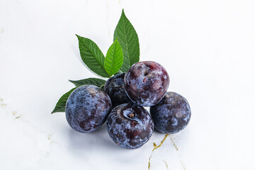 Raw purple plums heap with leaves