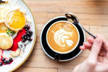 Breakfast Cup Of Coffee. Point of view of a woman's hand adding brown sugar to coffee on the dining table. Eating out lifestyle
