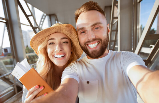 Excited couple making selfie at airport terminal, waiting for departure