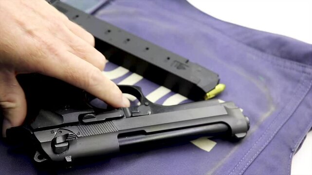 Black firearm hand pistol placed on top of a Police bullet proof safety vest 