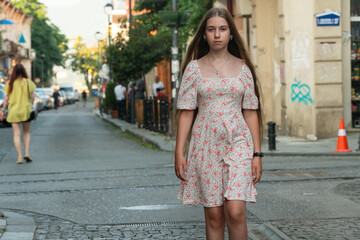 a girl in a dress stands near a wall with graffiti, teenager and graffiti, drawings on the walls, natural beauty, blonde, girl walking along the road