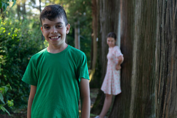 boy stands in the garden, boy's emotions, girl stands by a tree, sadness, resentment, smile, antics