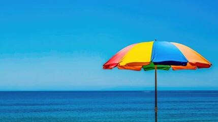 A colorful beach umbrella with the ocean in the background, space for text.